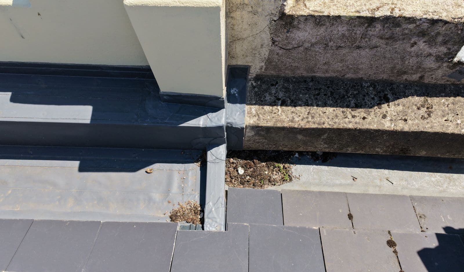 Aerial view of a parapet gutter, with the neighbouring side newly relined and the surveyed side weathered and holding debris